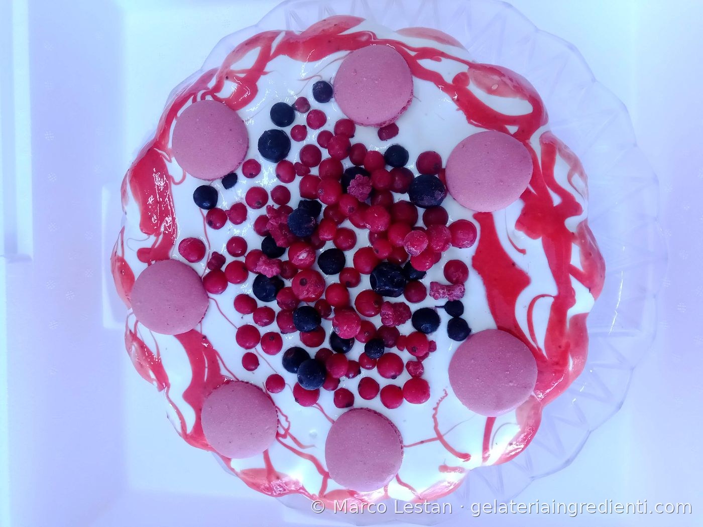 Decorazione torta gelato bianca con coulis di frutti rossi, macaron rosa e frutti di bosco freschi