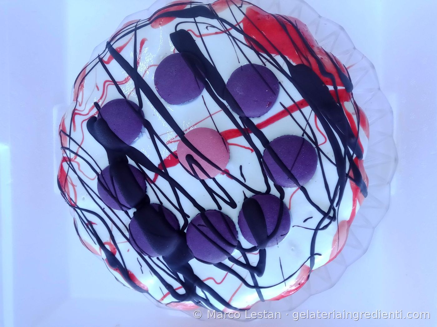 Decorazione torta gelato bianca con macaron viola e righe di cioccolato rosso e nero