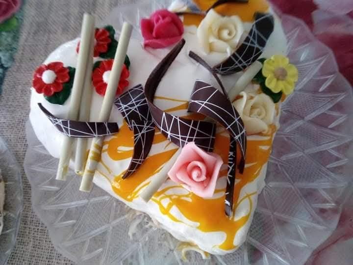Torta gelato a cuore bianca con fiori colorati e riccioli di cioccolato