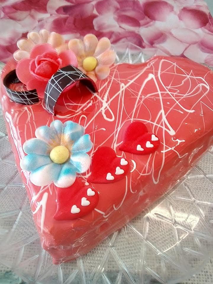 Torta gelato a cuore rossa con fiori pastello e cuoricini decorativi