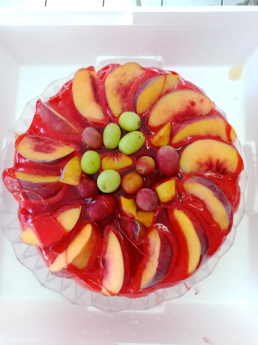 Torta gelato decorata con fette di pesca e uva fresca