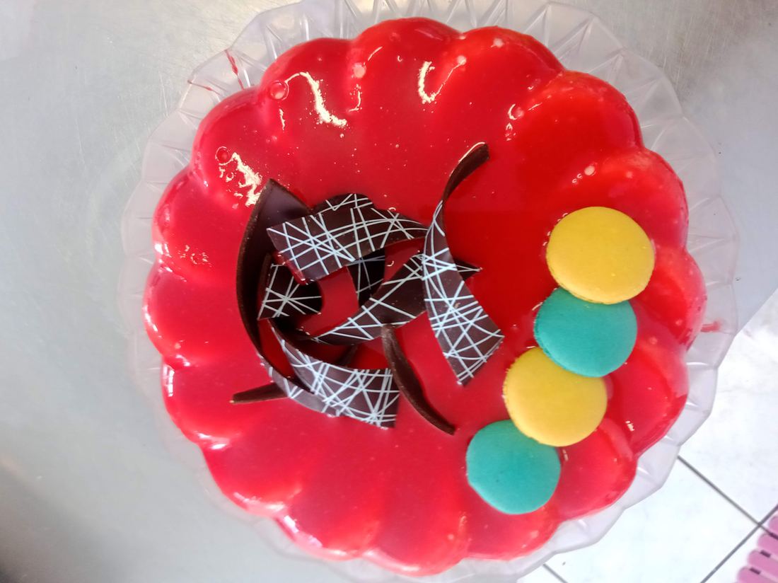 Torta gelato rossa con spirale di cioccolato decorato e macaron colorati