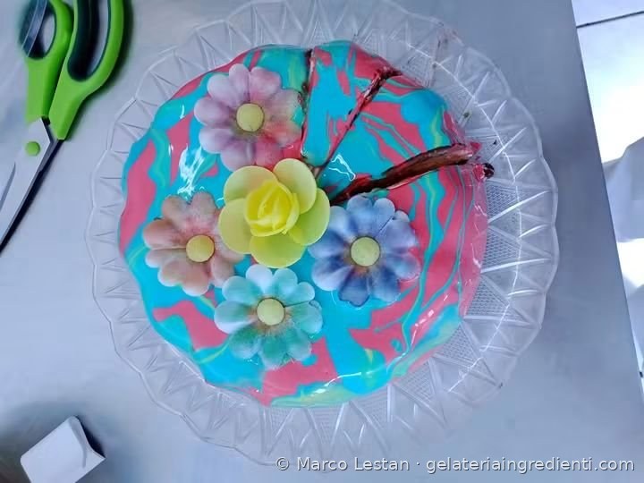 Torta gelato con glassa marmorizzata turchese e rosa e fiori colorati