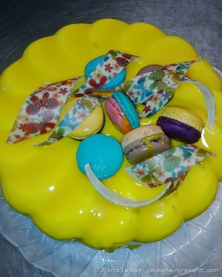 Torta gelato con glassa gialla, macaron colorati e decorazioni a farfalla