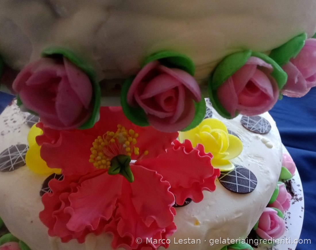 Boccioli di rosa rosa con foglie verdi e fiore rosso in pasta di zucchero su torta gelato nuziale