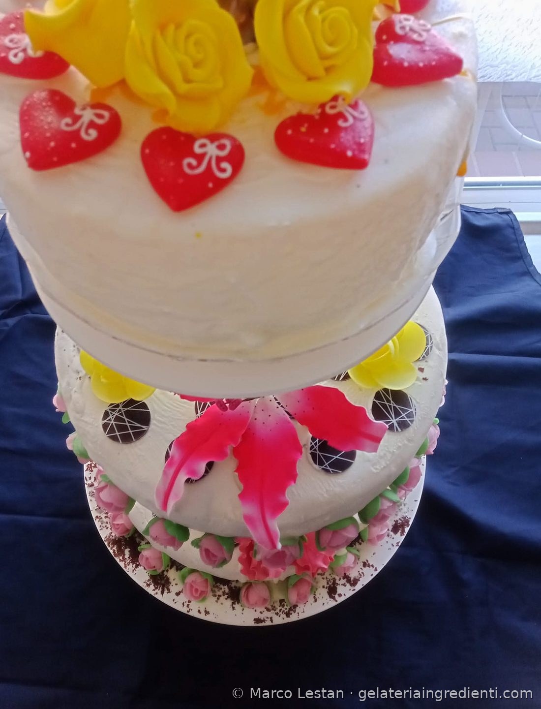 Torta gelato per matrimonio a tre piani con cuori rossi, rose gialle, giglio rosa e boccioli di rosa