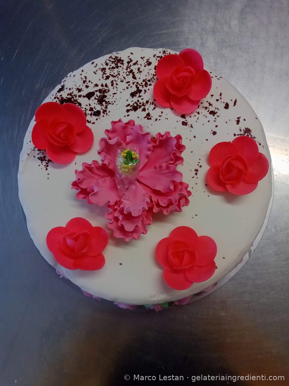 Torta gelato bianca con rose di ostia rosse, fiore in pasta di zucchero rosa e scaglie di cioccolato